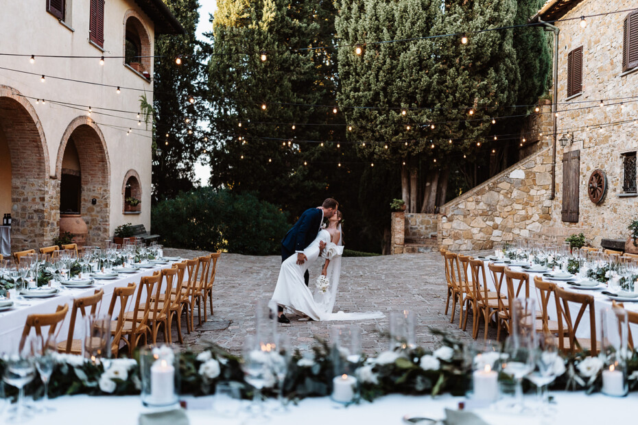 Bride and groom between long dinner tables in a courtyard
